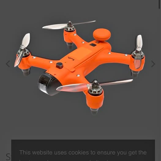 Orange quadcopter drone with four propellers and central camera mount.