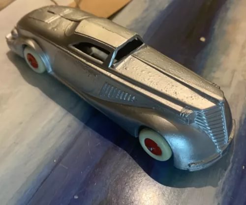 Vintage diecast toy car, blue with cream roof, front grille and red wheel accents.