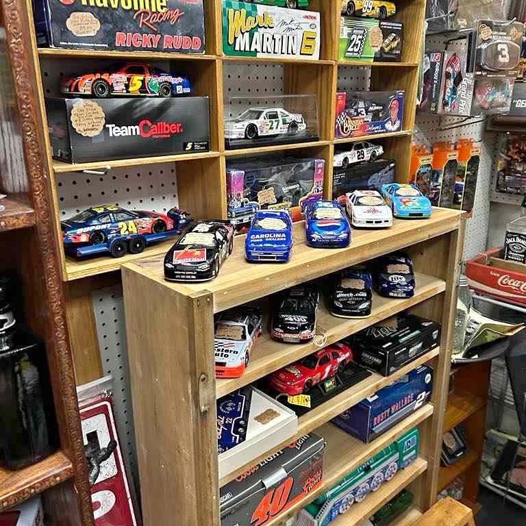 Diecast model cars displayed on wooden store shelves, assorted colors and designs