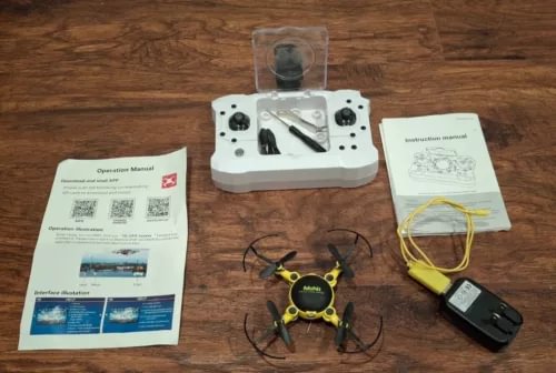 Foldable pocket drone with controller, manuals, and yellow cable