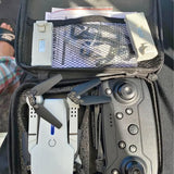 Foldable drone in open carrying case, gray body with white arms