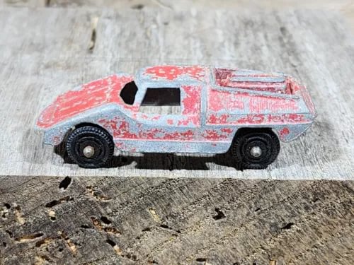Red diecast vintage toy car with black wheels, side view, detailed graphics