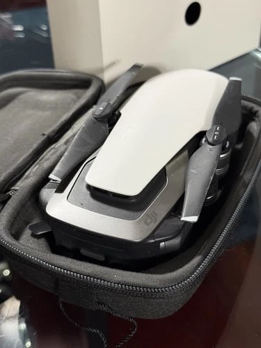 Camera drone in hard case, white body with folded propellers and remote accessories