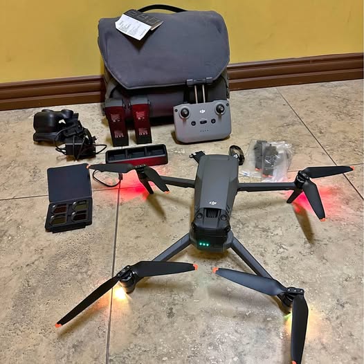 Foldable quadcopter drone with controller, propellers, and carrying case on floor