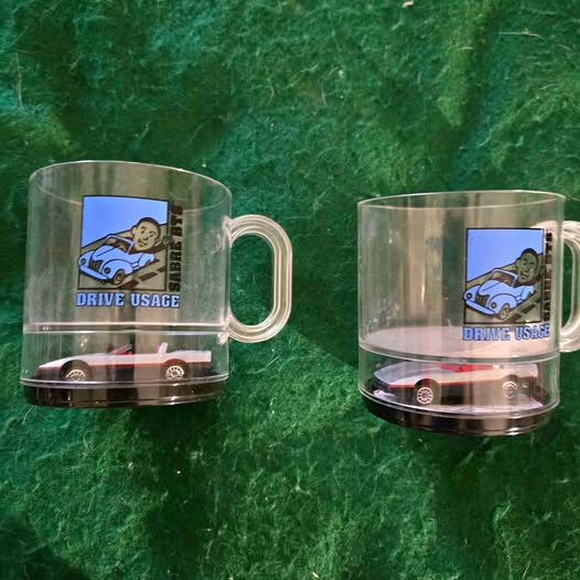 Clear novelty glass mug with handle, cartoon car badge and diecast car in base