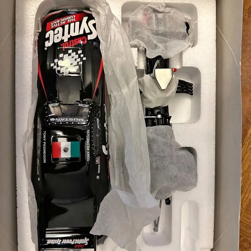 Black 1:24 scale diecast funny car in open blister packaging, front view with decals