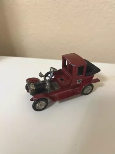 Vintage maroon die-cast car with black wheels, front three-quarter view.