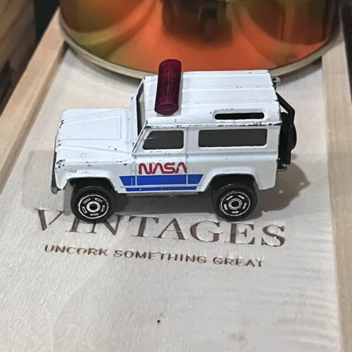 White NASA diecast toy vehicle with open back door, black wheels, detailed body