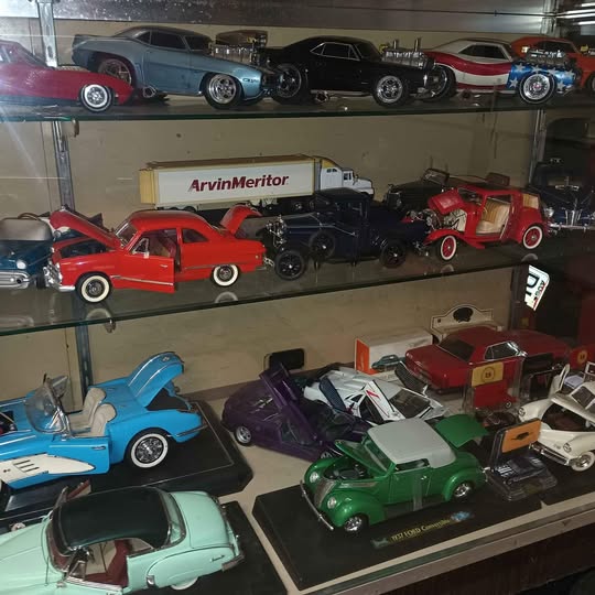 Glass-front diecast car display case with multiple miniature cars on shelves