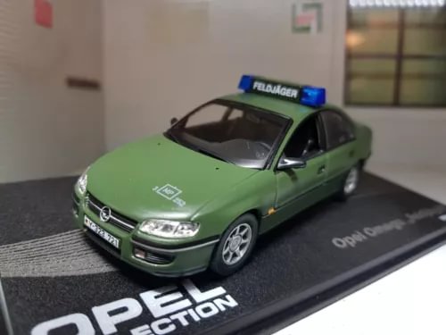 Green scale diecast police model car with roof badge, on display base