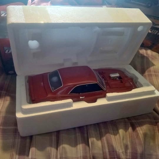 Red 1968 Pontiac Firebird diecast model car with black hood and white display base