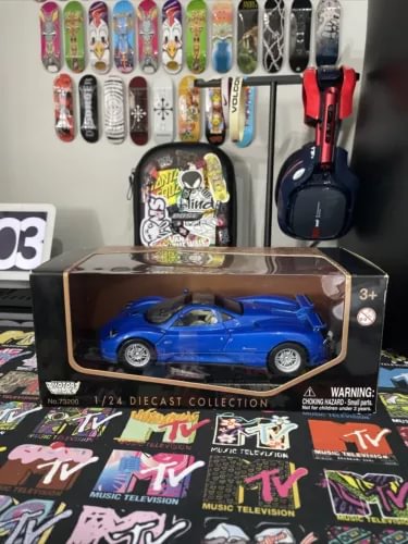 Blue 1/24 scale diecast model car in clear display box, with warning label