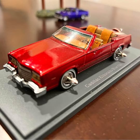 Red diecast convertible car model with chrome details on display base