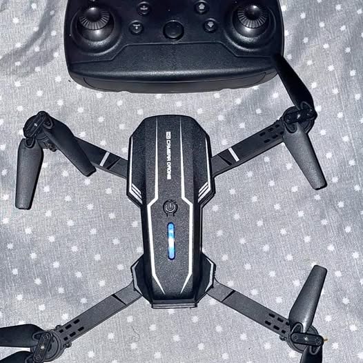 Black quadcopter drone with central body, LED indicator, and four extended arms.