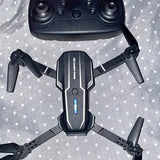Black quadcopter drone with central body, LED indicator, and four extended arms.