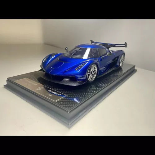 Blue 1:18 scale diecast sports car model on dark display base, front three-quarter view