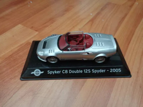 Silver convertible diecast sports car with burgundy interior, on display base.
