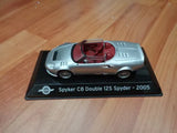 Silver convertible diecast sports car with burgundy interior, on display base.