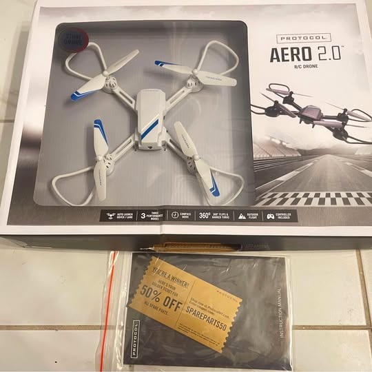 Remote-controlled quadcopter drone set in retail box, white with blue prop accents