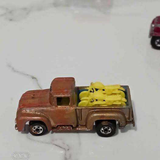 Diecast toy pickup truck with yellow engine detail, brown body.
