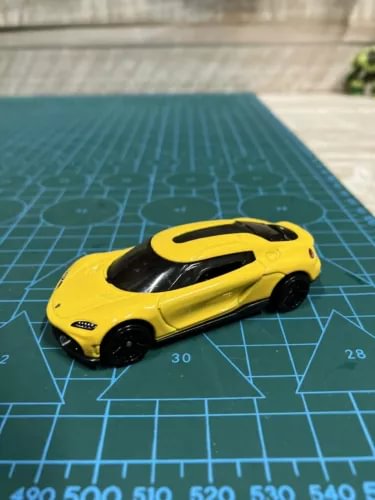Yellow diecast toy car model with black roof and hood details, small 1:64 scale