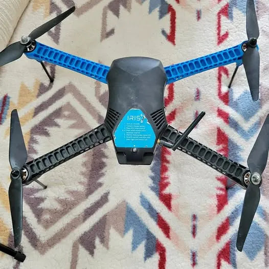 Quadcopter drone with blue propeller arms, black body and four black propellers
