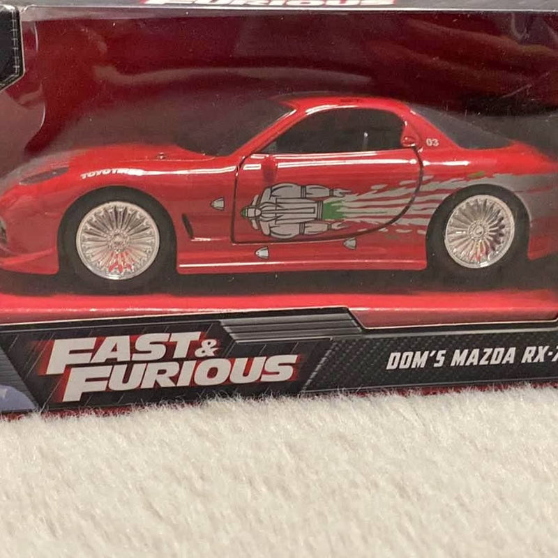 Red diecast race car model with detailed engine graphic, on Fast & Furious display box