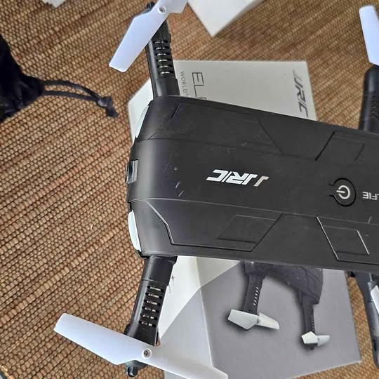 Foldable black drone with camera housing, four propellers, and landing legs