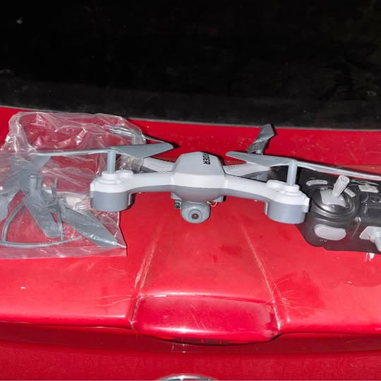 Red quadcopter drone with camera and four propeller arms