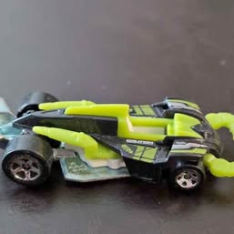 Hot Wheels diecast race car in lime green and black, detailed body with spinning wheels