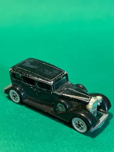 Dark green classic diecast car with chrome grille and hood scoop, front 3/4 view