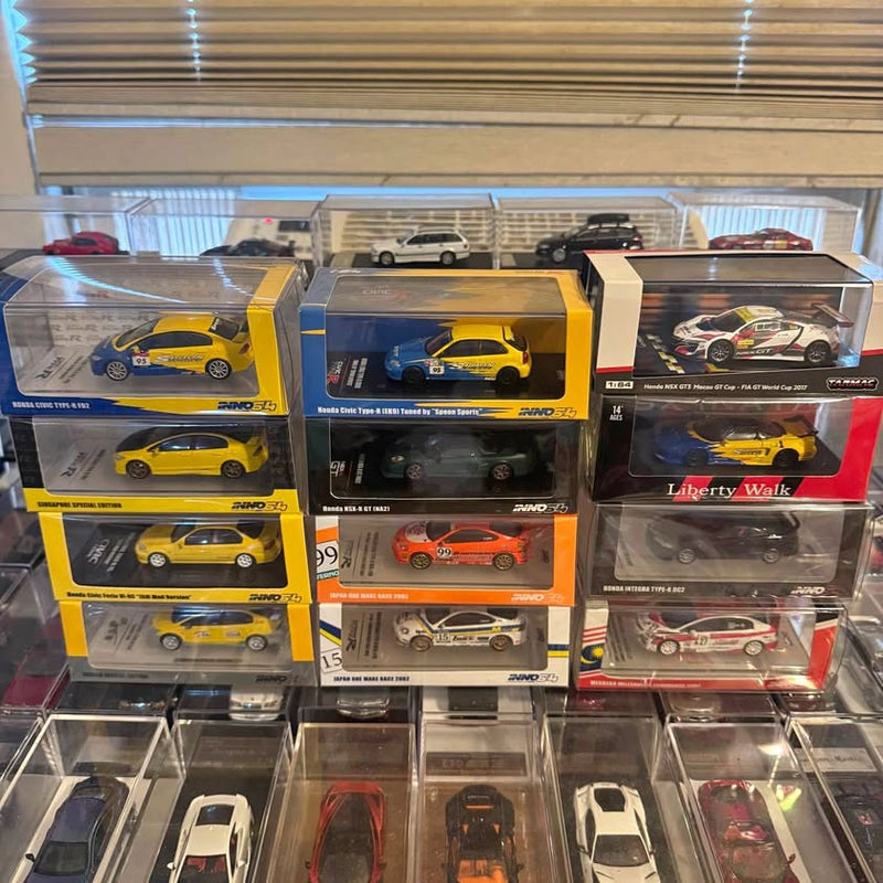 Set of boxed diecast race car models, yellow and red cars in clear display cases