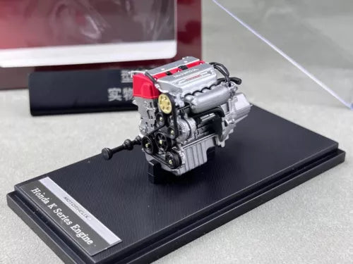 Diecast car engine model with red valve cover on black display base