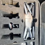 Folded drone with four propellers inside molded protective case, compact white body