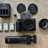Sony ZV1 vlogging camera with lens, furry mic, and accessory batteries and charger.