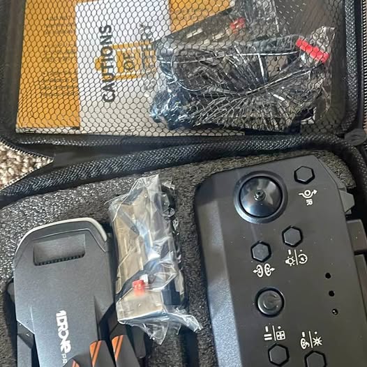 Grey drone remote controller with button controls and accessory parts in bag