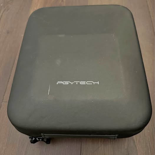 Hard-shell drone case in dark gray, front logo, zipper edge visible