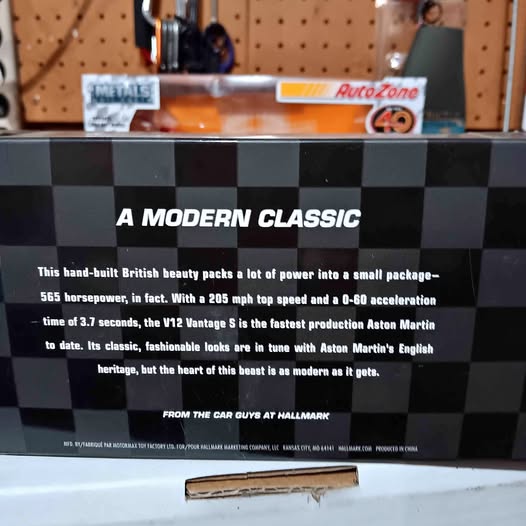 Diecast car model in retail box with checkered pattern and orange front artwork