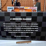 Diecast car model in retail box with checkered pattern and orange front artwork