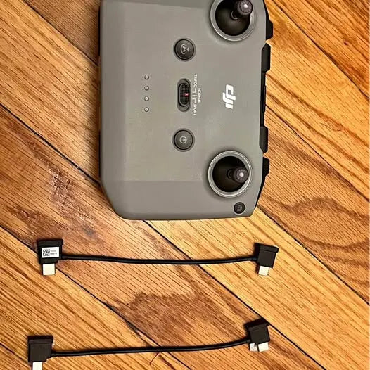 Gray replacement drone controller with joystick sticks and two attached cables, ports on back.