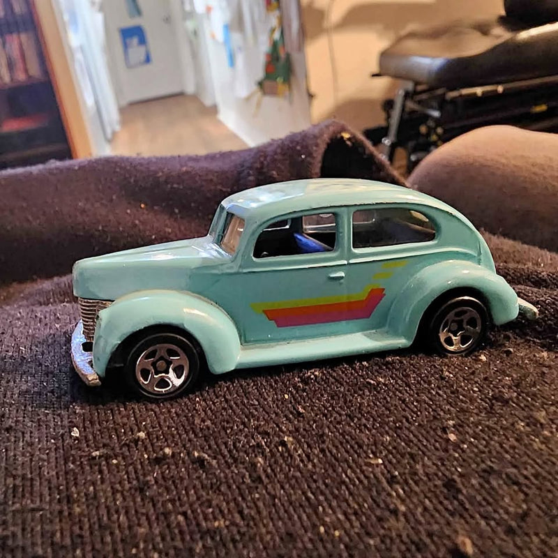 Light blue diecast toy car with red-yellow stripe on side and black wheels