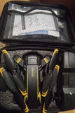 Foldable quadcopter drone with black body and yellow markings, inside mesh carry case