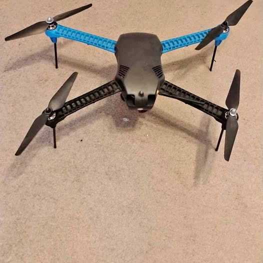 Quadcopter drone with blue guards, black body, four propellers.