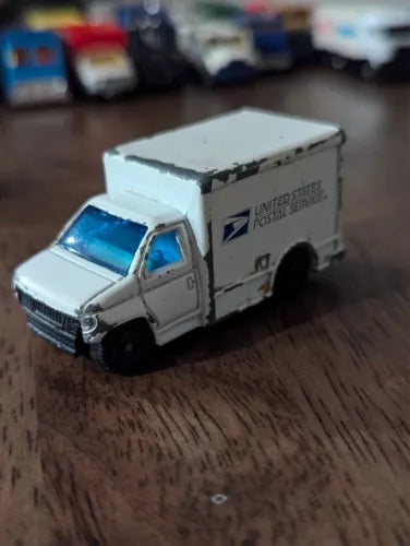 White diecast step van delivery truck with open grille and blue windows, front 3/4 view