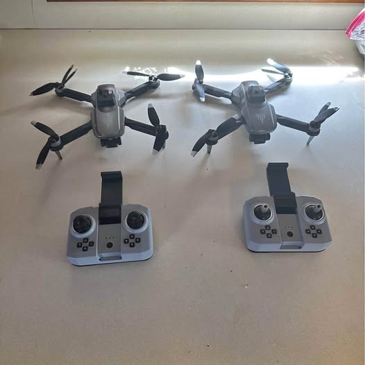 Two foldable quadcopter drones with gray controllers, each with dual joysticks and screens