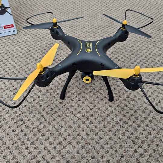Black quadcopter drone with four yellow propellers and landing legs