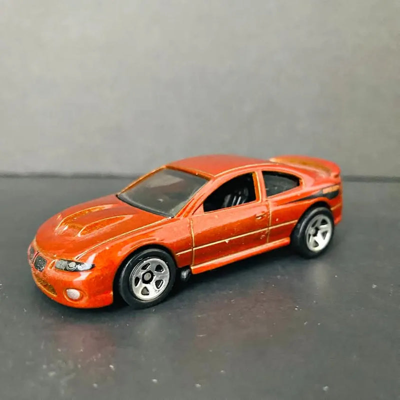 Orange diecast sports car with black grille and chrome wheels, side view