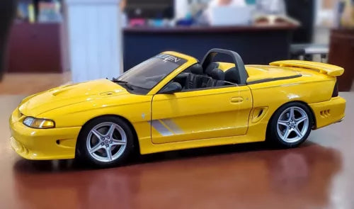 Yellow convertible die-cast sports car with black interior and silver wheels, front 3/4 view