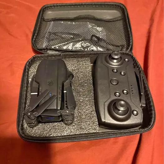Black drone controller and drone in zippered carrying case with accessories.