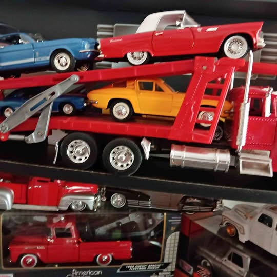 Red diecast truck transporter with orange and blue cars on upper deck